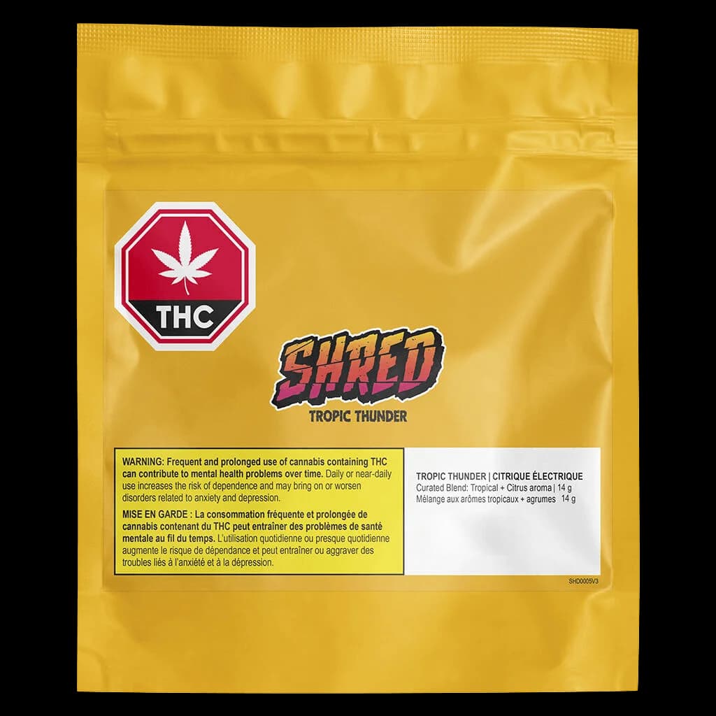 SHRED Tropic Thunder 14g cannabis dried flower package with yellow pouch, THC badge, and tropical citrus branding